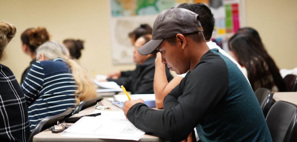 Una foto de clase de estudiantes tomando notas.