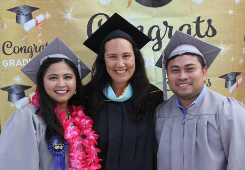 NOCE counselor posing with two students in their cap and gowns