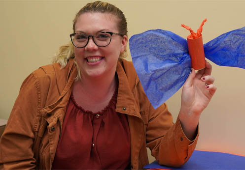 A smiling NOCE student holding up her papier-mâché butterfly.