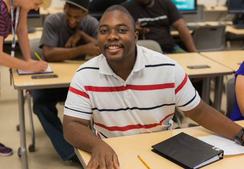 A smiling DSS student at his desk