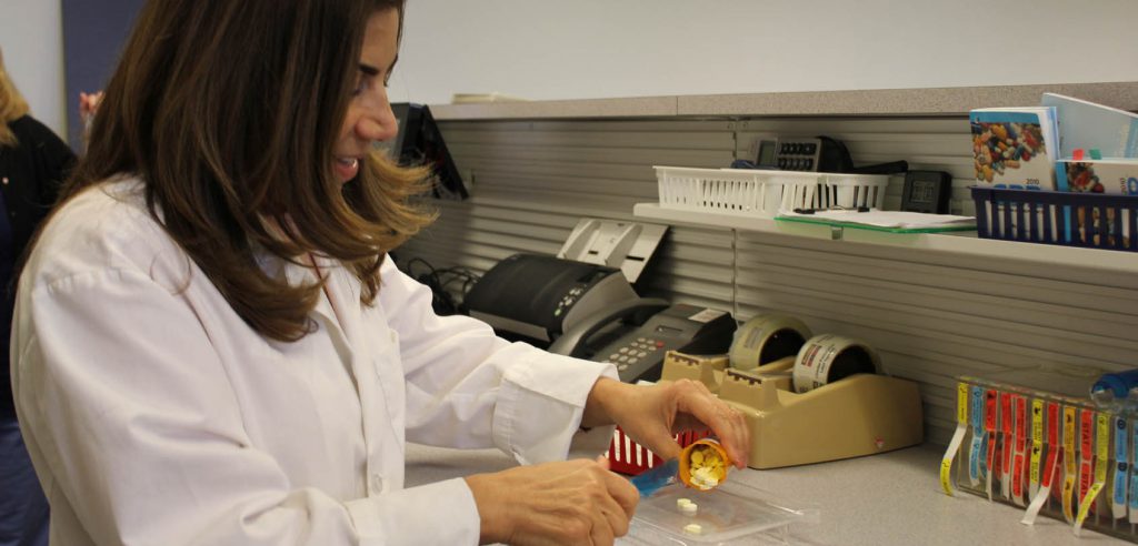 Un estudiante de técnico de farmacia que separa el número de pastillas de una receta.