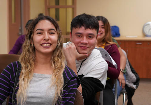 A photo of two smiling ESL students sitting at their desks. 