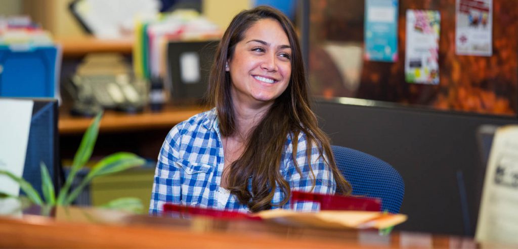 A photo of an Admissions and Records assistant at the front desk.