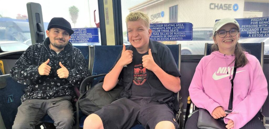 three students riding on a OCTA bus, smiling for the camera.