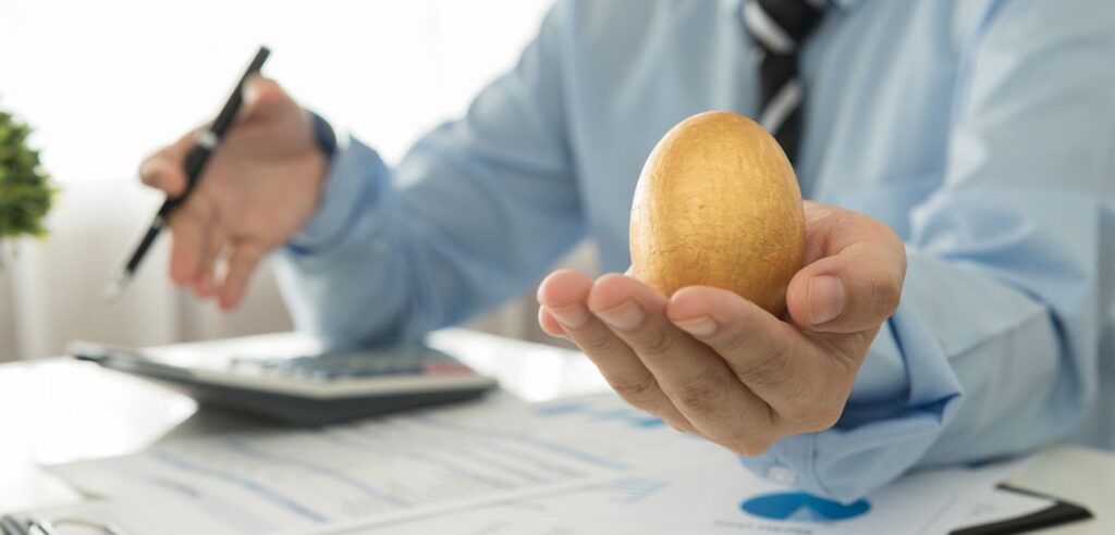 A financial health counselor reviewing paper work while holding up a golden egg.