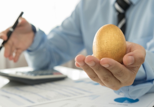 A financial health counselor reviewing paper work while holding up a golden egg.