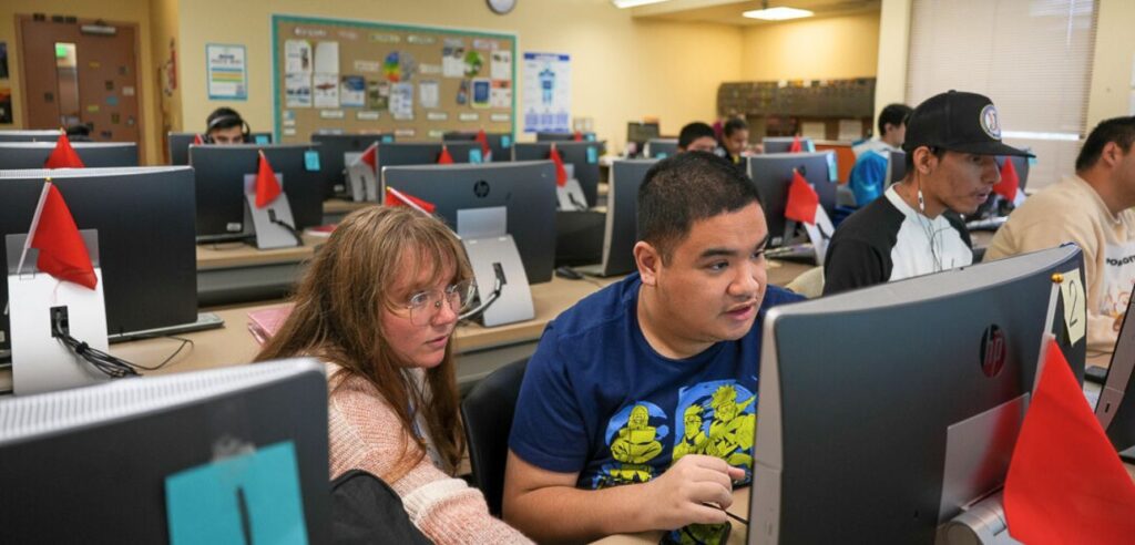 DSS students in an advanced computer class. A female teacher is assisting a male student.