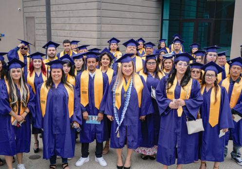 A group photo of CTE graduate students in their blue caps and gowns and a golden sash.