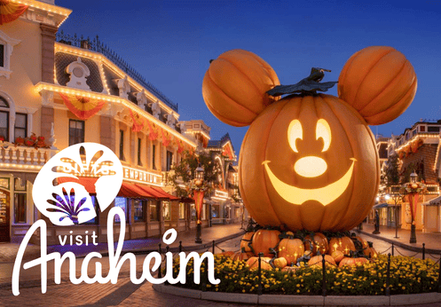 Visit Anaheim Logo with a photo of Disneyland's main street decorated for Halloween with the giant pumpkin mickey mouse