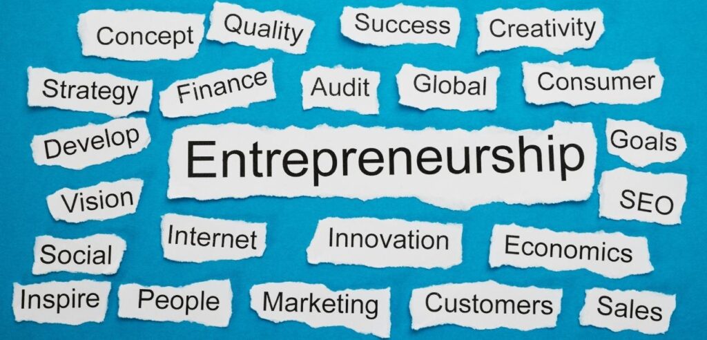 A blue background with strips of white paper with words like Entrepreneurship, goals, innovation, etc.