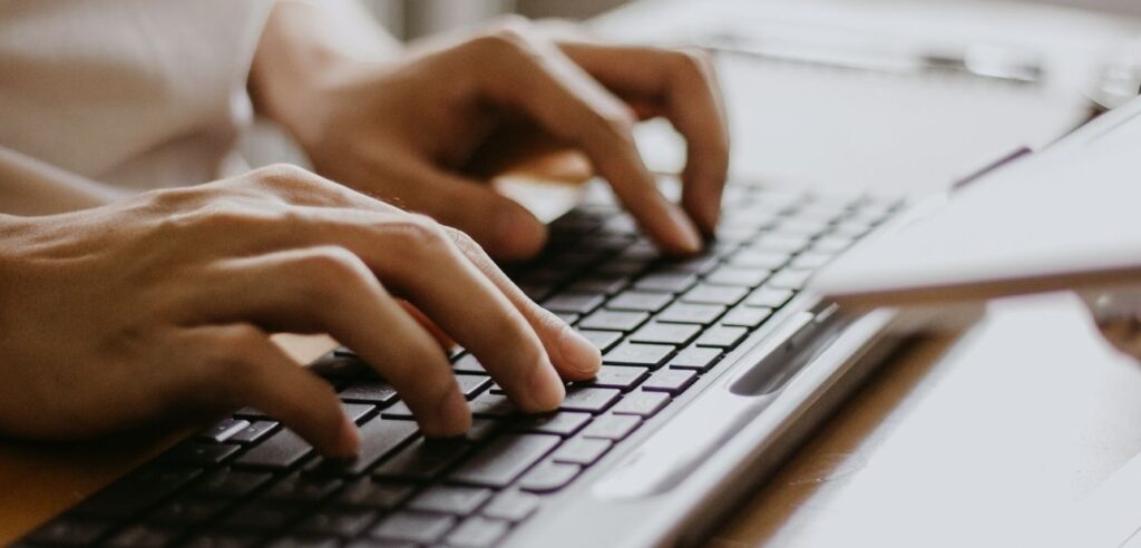 Hands typing on a flat black keyboard.