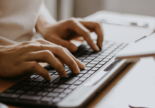 Hands typing on a flat black keyboard.