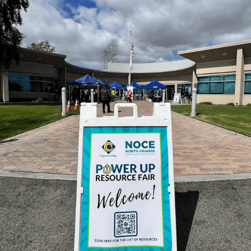 NOCE Cypress Center hosting a Power Up Resource Fair in 2024. In the Cypress Center circle, there is a bunch of EZ up tents and a welcome sign on a white sandwich board.