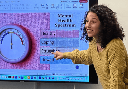 Teacher points to the presentation during a class about mental wellness in our homes.