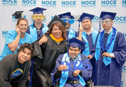 A group photo of graduating Disability Support Services Program students with their counselor, and teachers. The students are all dressed up in their dark blue cap and gowns.