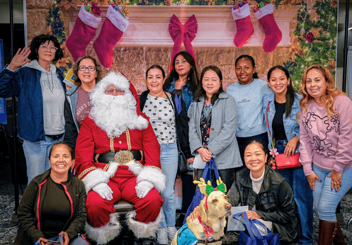 A group of ESL students posing with Santa Claus at the December 2025 Power Up Resource Fair