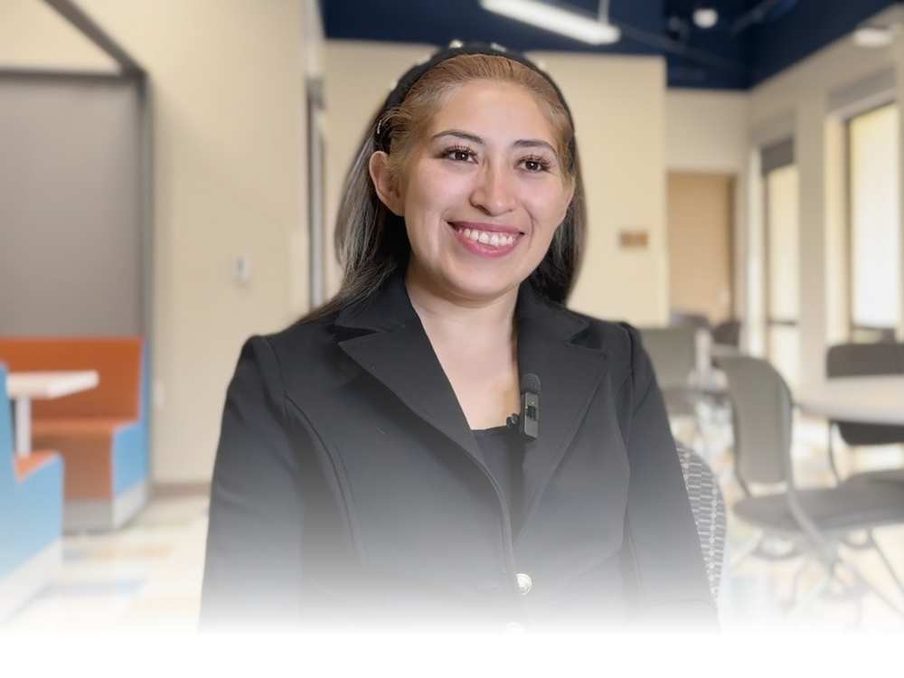 A smiling female student wearing a black blazer and blouse for an interview.