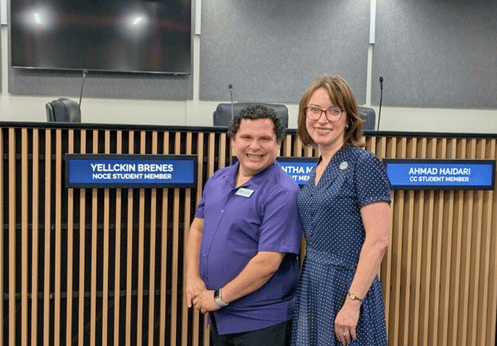 Yellckin Brenes and Valentina Purtell posing together in front of a backdrop with nameplates that read "Yellckin Brenes - NOCE Student Member."